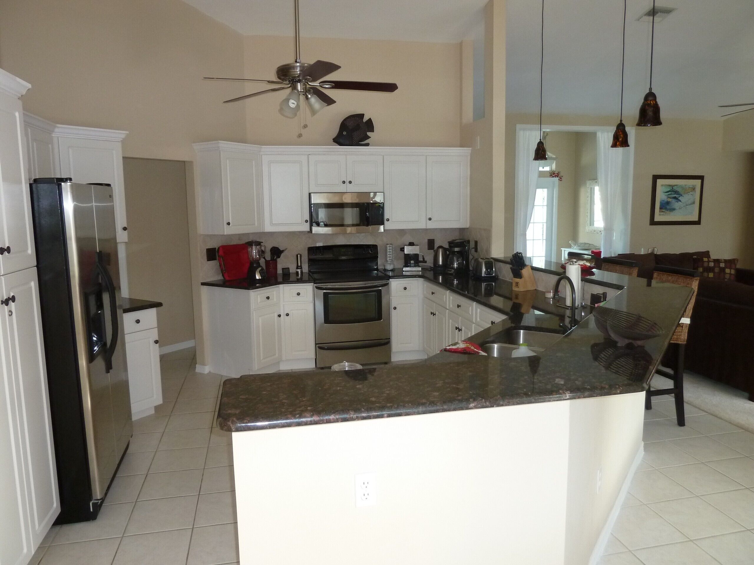 A modern kitchen with white cabinets, stainless steel appliances, and a granite countertop island.