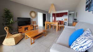Ein Wohnzimmer mit Fernseher, Holzmöbeln, einer Couch und einem Essbereich.