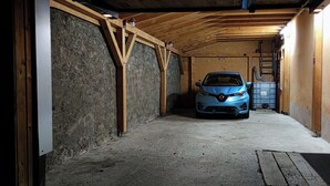 A car parked in a narrow, dimly lit garage with wooden beams and concrete walls. - Between Colmar and Grand Ballon 
Townhouse with garden and double garage (Guebwiller)