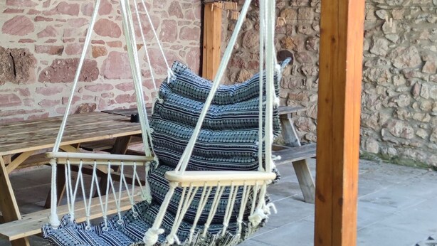 A wooden swing chair with patterned cushions hanging from a ceiling beam. - Between Colmar and Grand Ballon 
Townhouse with garden and double garage (Guebwiller)