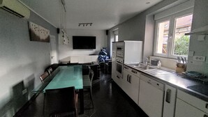 A modern kitchen with a dining area, a built-in oven, and a window with a view of greenery outside. - Between Colmar and Grand Ballon 
Townhouse with garden and double garage (Guebwiller)