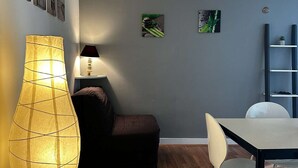 A modern living room with a wooden floor, a dining table, a sofa, and a floor lamp.