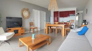 A modern living room with a TV, sofa, coffee table, and dining area. - Pasino bright apartment +Terrace15m2, seafront, WIFI, Parking included, 6p,N°5 (Lacanau Océan)