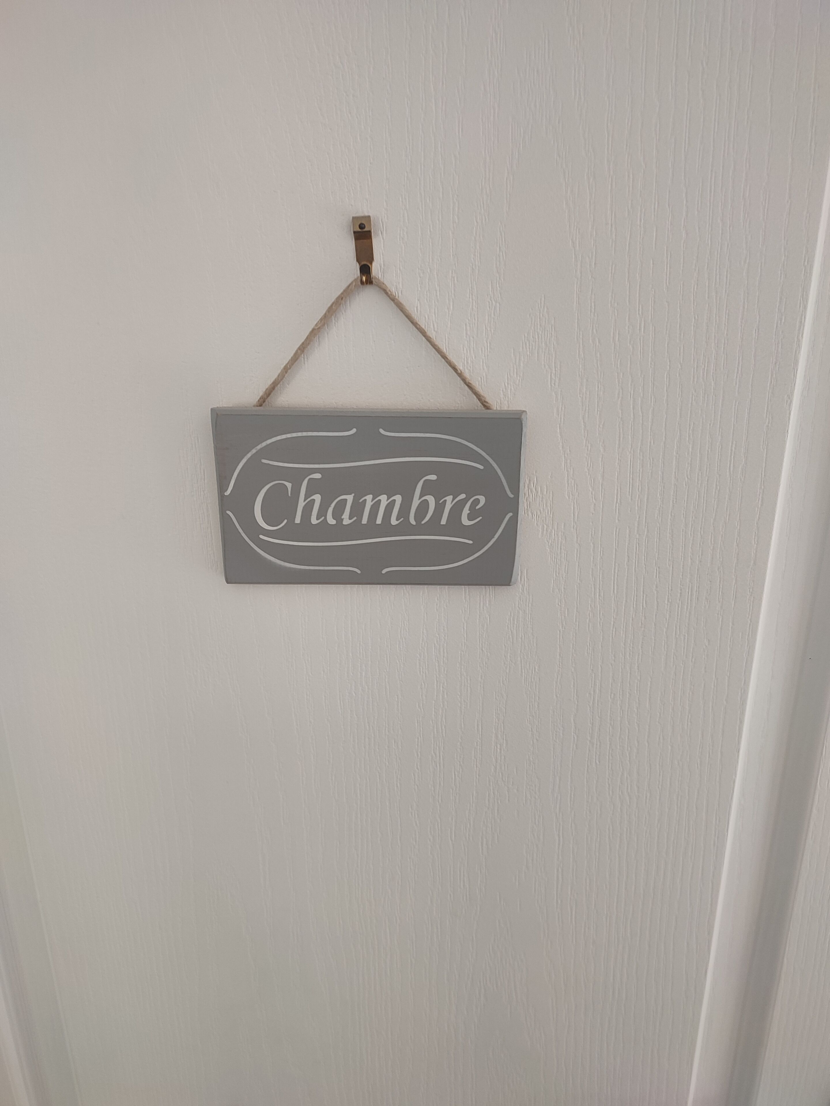 Une pancarte avec le mot « Chambre » est accrochée à un mur blanc.
