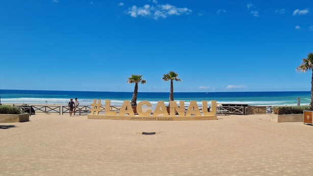 A beach with a sign reading "LACANHA" and palm trees.