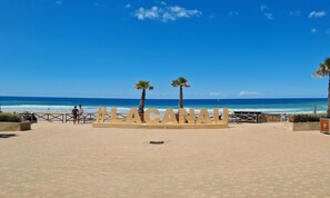 Una playa con un cartel que dice "LACANHA" y palmeras.