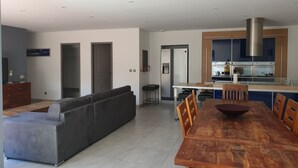 A modern kitchen with a stainless steel refrigerator, wooden cabinets, and a central island with stools.