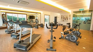 Une salle de sport équipée de tapis de course, de vélos elliptiques et de matériel de musculation.
