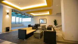 Un hall d’entrée moderne doté d’un haut plafond, d’un éclairage encastré et d’un espace salon avec des canapés et une table basse.