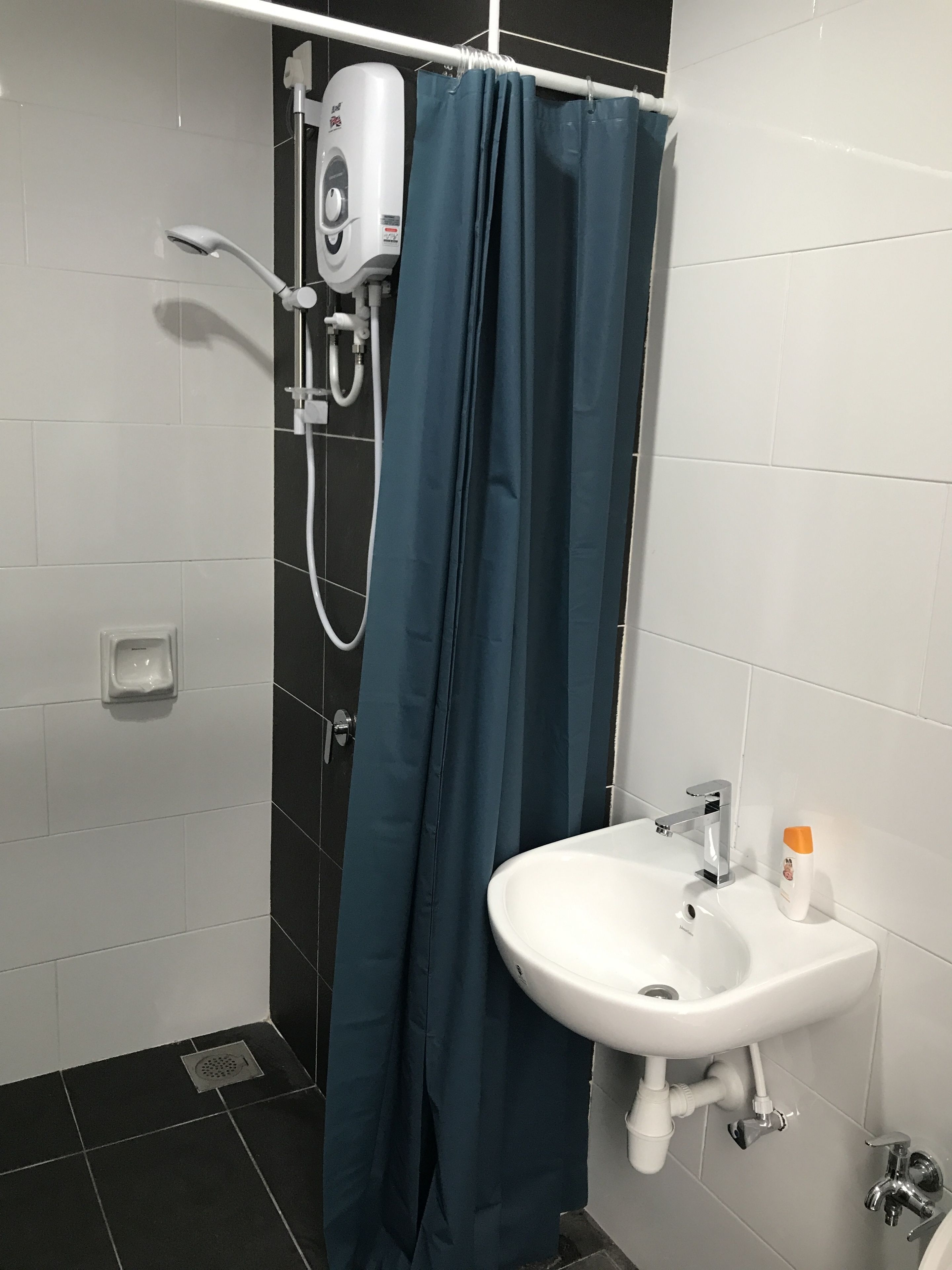 A bathroom with a shower, a sink, and a hand dryer.