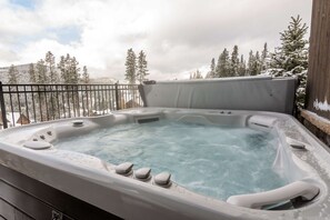 Un bain à remous sur un balcon, avec une chaîne de montagnes enneigées en arrière-plan.