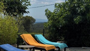 A poolside area with lounge chairs and a stone-tiled floor.