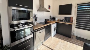 A compact kitchen with a built-in oven, microwave, and dishwasher, featuring modern appliances and a tiled backsplash.