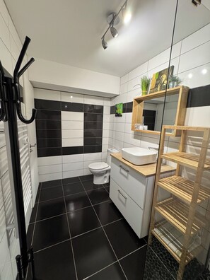 A modern bathroom with a black and white tiled floor, a white sink, and a wooden vanity. - Gîte l'olivade For 4 pers private pool (Flayosc)
