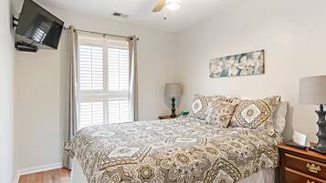 Cozy retreat with a large bed, flat-screen TV, and ceiling fan.