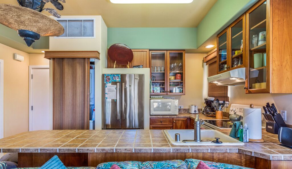 A kitchen with a central island, stainless steel appliances, wooden cabinets, and a microwave.