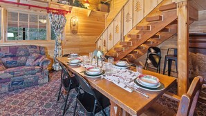 Un interior de madera con una mesa de comedor preparada para cuatro personas, un sofá y una escalera.