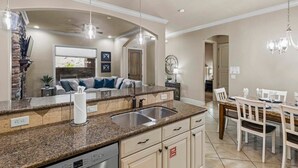 A kitchen with granite countertops, a dishwasher, and a dining area with a table and chairs.