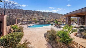 A backyard with a swimming pool, patio furniture, and a stone building.
