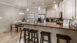 A kitchen with a central island, bar stools, a dining table with chairs, and a 'NO SMOKING' sign.