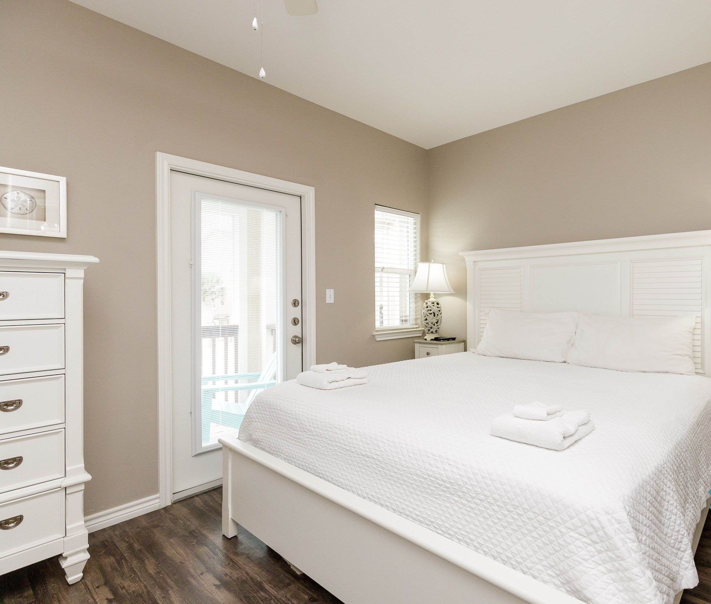 Une chambre à coucher propre et blanche, avec un lit, des tables de chevet et une commode.
