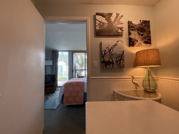 A bedroom with a bed, a nightstand, a lamp, and artwork on the wall.