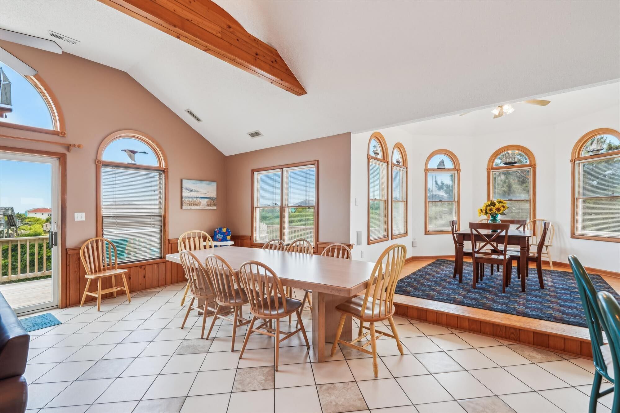 Un comedor amplio con una gran mesa y numerosas sillas, ventanas arqueadas y vistas al exterior.