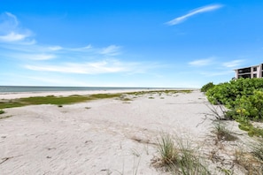 A beach with a building and vegetation.