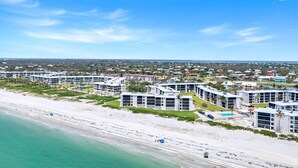 A coastal hotel with multiple buildings, a beach, and a clear sky.