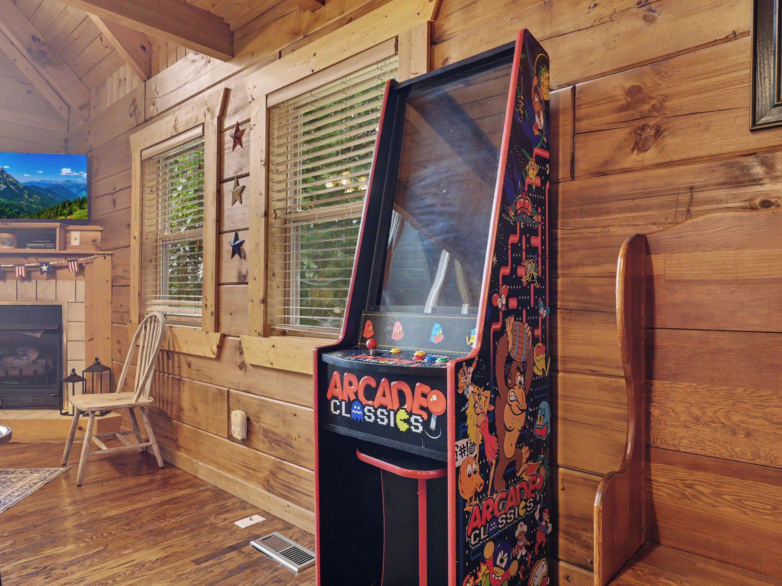 A wooden cabin interior with a vintage arcade game machine labeled 'Arcade Classics' and a rustic wooden chair.