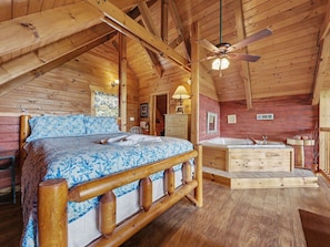 L’intérieur d’un chalet en bois comprend un lit, une salle de bain avec baignoire et un ventilateur de plafond.