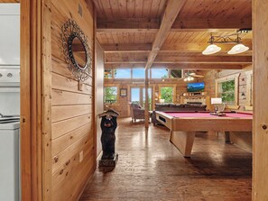 A wooden interior with a pool table, a television, and a fireplace.