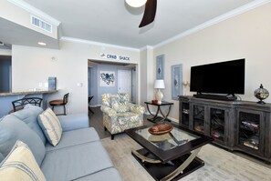 A living room with a sofa, armchair, television, and a cabinet with glass doors.