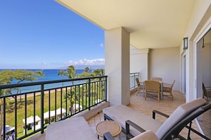 Enjoy the ocean view from this furnished balcony with a sofa, chairs, and table.