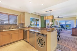 A modern kitchen with granite countertops, stainless steel appliances, and a built-in washer and dryer.