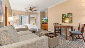 A hotel room with a sofa, a coffee table, a TV, a dining table with chairs, and a ceiling fan. - Maui Resort Rentals: Westin Ka'anapali Ocean Resort 2BR Direct Oceanfront Villa (Lahaina)