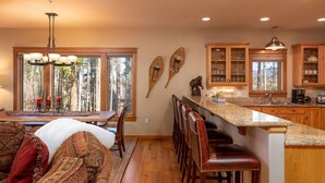 A modern kitchen with wooden cabinets, a granite countertop, and a dining area with a chandelier.