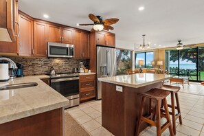 Una cocina moderna con armarios de madera, electrodomésticos de acero inoxidable y una isla grande con taburetes de bar.