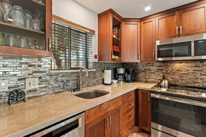 A kitchen with wooden cabinets, a stainless steel microwave, and a built-in oven.