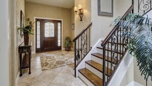 A foyer with a wooden staircase, a decorative rug, a potted plant, and a wall-mounted light fixture. - 21 Windjammer-Private Pool, views of the 10th tee of Harbour Town Golf Links (Hilton Head Island)