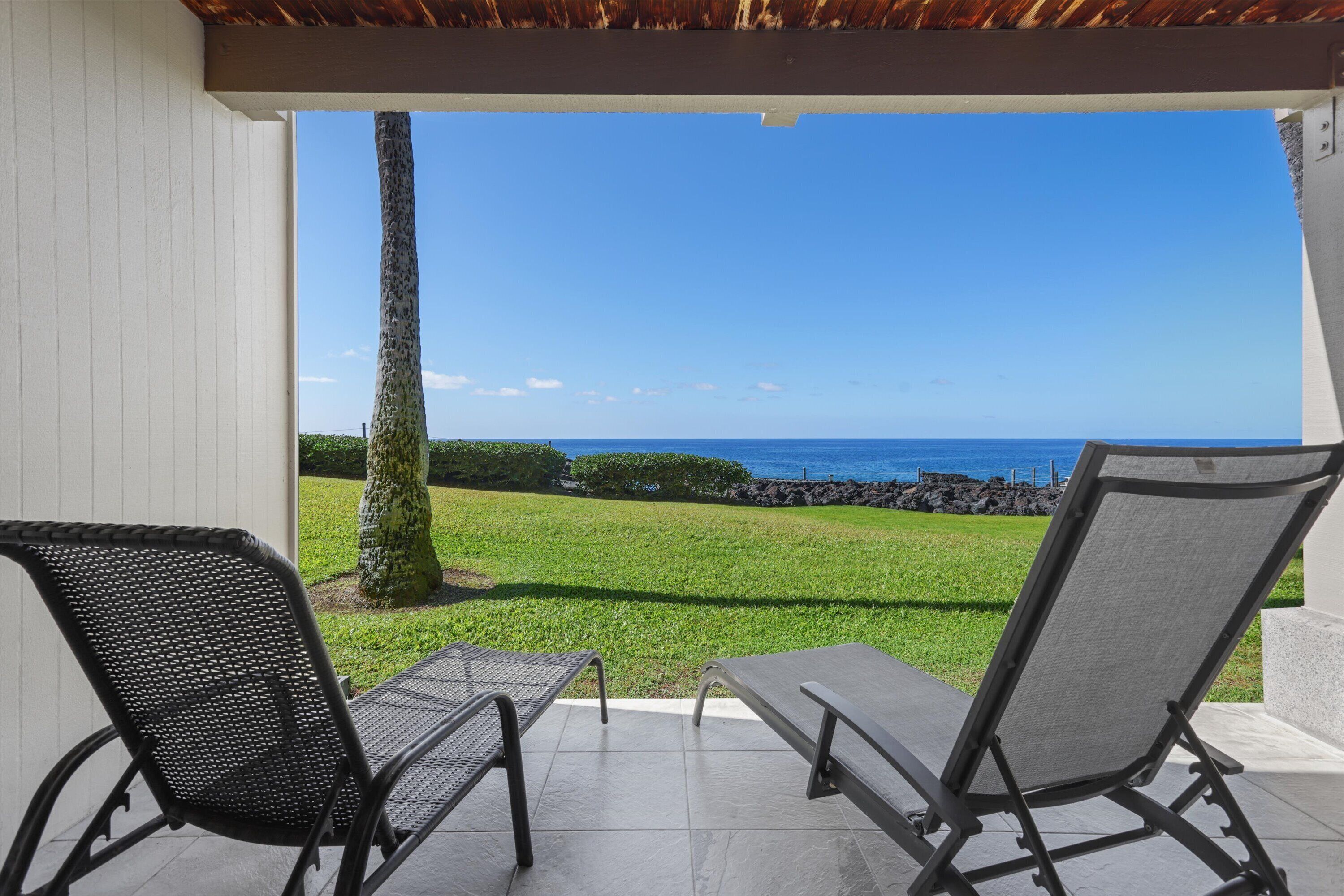 A patio with two lounge chairs and a view of the ocean.