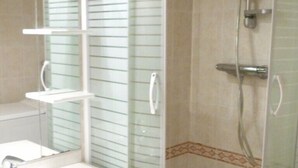 A bathroom with a glass-enclosed shower, a white sink, and a mirror above it. - Centre d'Arcachon, emplacement idéal près de la plage (ARCACHON)