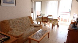 A living room with a sofa, a coffee table, a dining table with chairs, and a view of the outside. - Centre d'Arcachon, emplacement idéal près de la plage (ARCACHON)