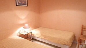 A small, single-bed room with a bedside table and lamp, a chair, and a framed picture on the wall. - Centre d'Arcachon, emplacement idéal près de la plage (ARCACHON)