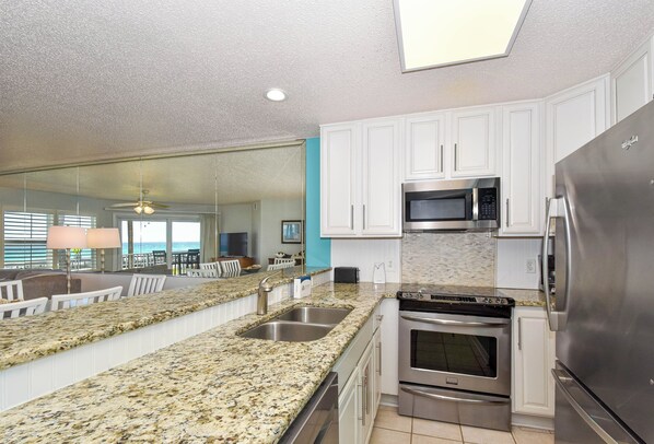 A kitchen with granite countertops, stainless steel appliances, white cabinets, and a view to the outside. - PET FRIENDLYđśBeachy condo w/Gulf views in a gated community! đ´ (Miramar Beach)