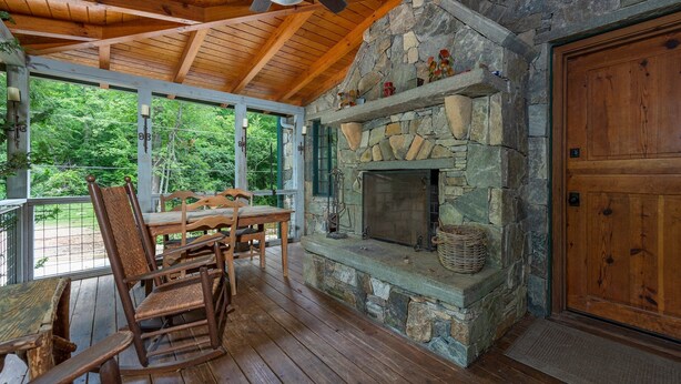 Una terraza de madera con chimenea de piedra, mobiliario de madera y un gran portón de madera.