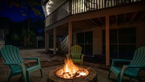 Un foyer avec des chaises disposées autour, un patio couvert et un escalier menant à un niveau supérieur.