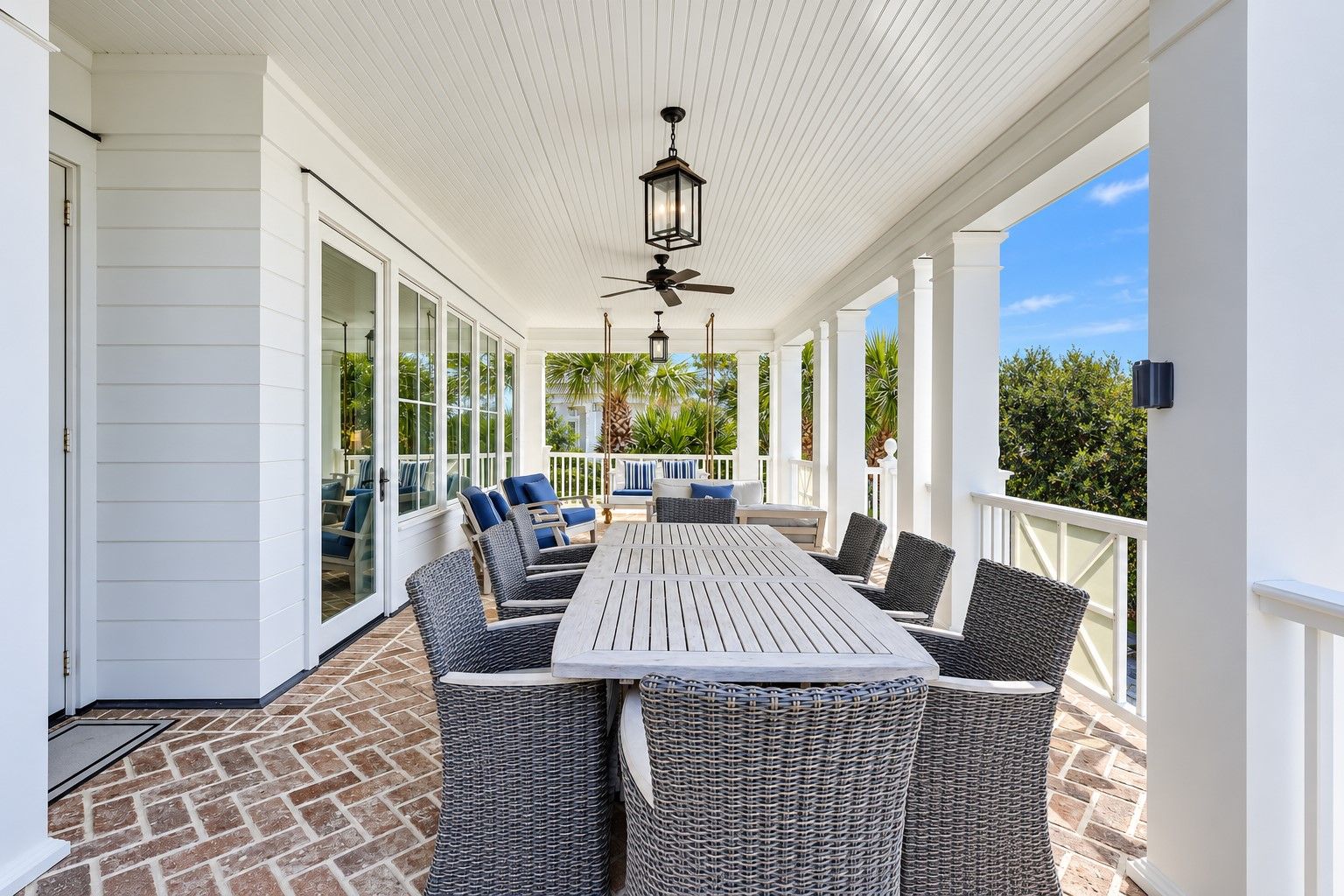 Une terrasse couverte avec une table et des chaises, un ventilateur de plafond et une vue sur l’extérieur.