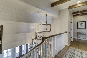 Una escalera con balaustres blancos y un tapete estampado, que conduce a una habitación con una ilustración enmarcada de un pez en la pared.