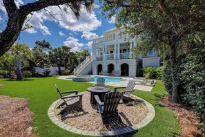 A two-story house with a pool, outdoor seating, and a well-maintained lawn.